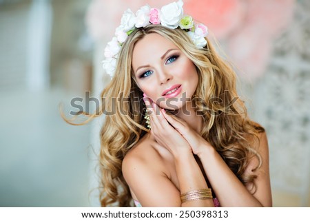 Very beautiful sensual girl with curly blond hair and a wreath of delicate spring flowers, close up