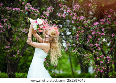 Very beautiful happy bride blonde curly hair in a white dress smiles on the background of Apple blossoms