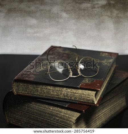 Two old books with antique reading glasses on colorful background