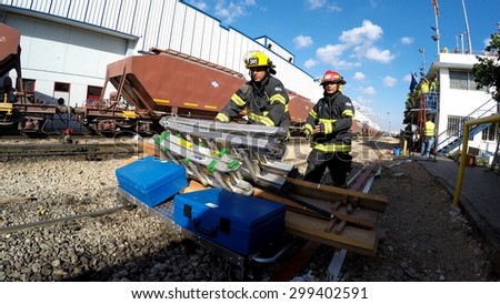 HAIFA, ISRAEL - JUNE 30, 2015: Firefighters from Northern Israel with protective gear bring tools during simulation drill of leak of Bromine chemical in a container car of train