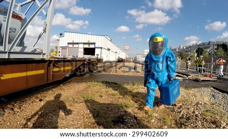 HAIFA, ISRAEL - JUNE 30, 2015: Firefighter from Northern Israel with protective gear brings case with tools during simulation drill of leak of Bromine chemical in a container car of train