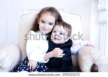 Brother and sister sitting indoors smiling and hugging