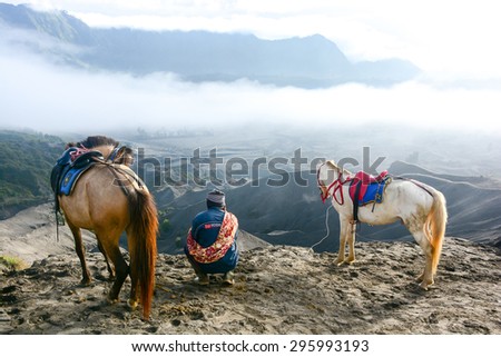 JAVA, INDONESIA - JANUARY 24, 2013 : Unidentified man with horses for tourist rent and beautiful landscape at Mount Bromo in East Java , Indonesia.