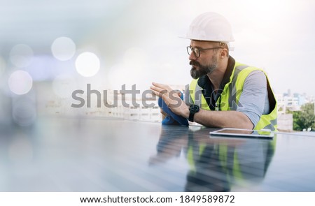 Rooftop solar power plant engineers sitting and examining photovoltaic panels. Concept of alternative energy and its service. Engineer energy power man worker at site.