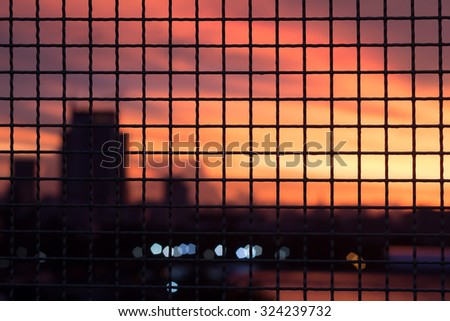 metal grid fence and could sky city sunset abstract blur.