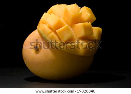 Whole \'Kensington Pride\' mango with inverted mango cheek on black under spotlight