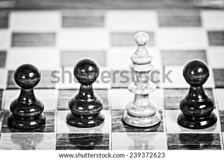 Old wooden chess pieces on a chessboard in black and white