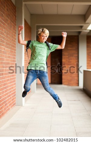 happy male high school student jumping up in school