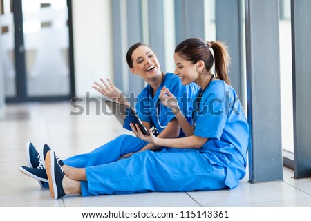 two female young nurses having fun with tablet computer during break