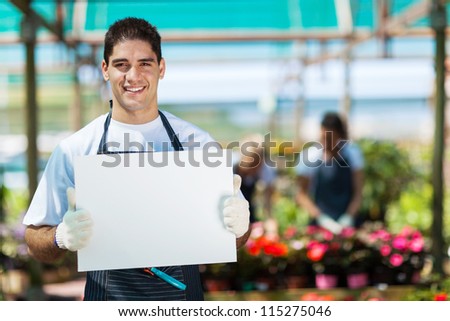 happy gardener holding white board in greenhouse