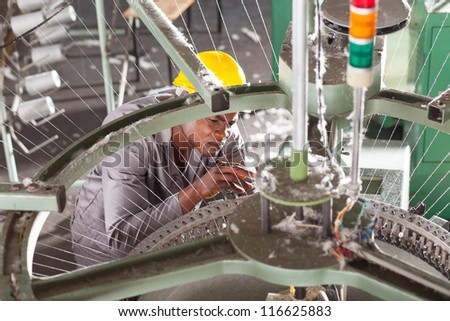 african american textile factory technician repairing weaving loom