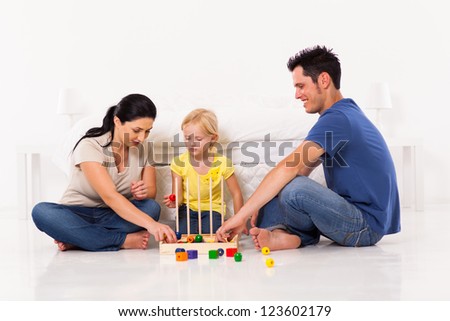 happy family playing toy game with daughter on bedroom floor