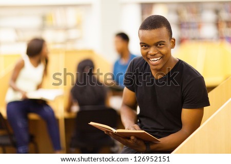 happy male african college student reading book in library