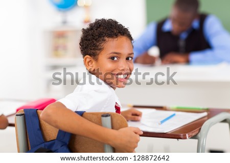 cute elementary schoolboy looking back in classroom