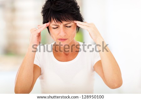 mid age woman having headache and massaging forehead