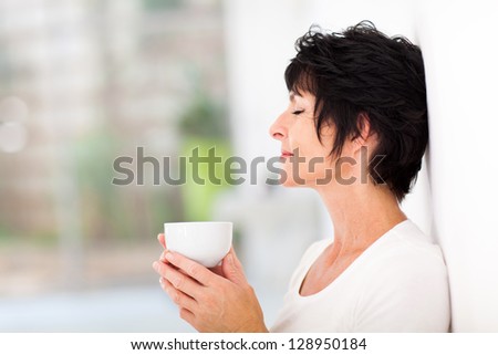 beautiful mature woman enjoying a cup of coffee at home