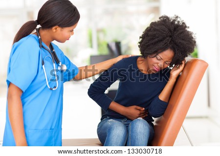 young african nurse comforting female patient in doctor\'s office