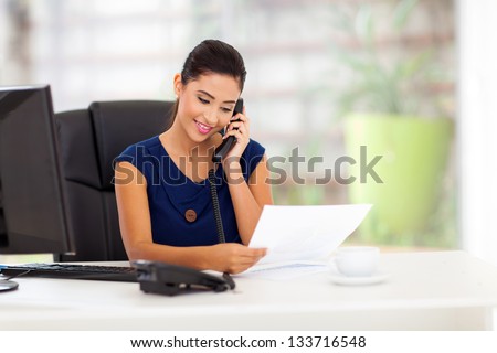 smart young businesswoman on the telephone and reading report
