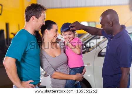 friendly african american auto mechanic playing with customer\'s little girl