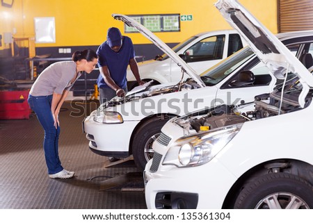 african mechanic and female customer in front her car with bonnet open