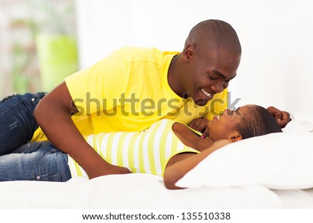 happy young african couple lying on bed