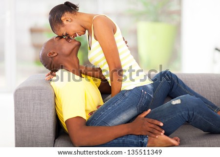 beautiful young african woman sitting on boyfriend flirting