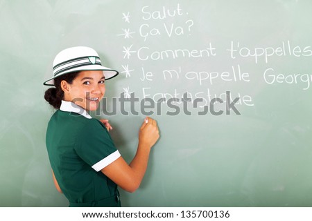 portrait of cute french schoolgirl writing on chalkboard