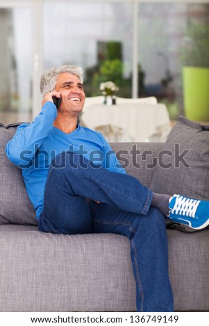 happy middle aged man talking on cell phone at home