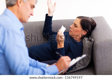 upset middle aged woman talking to her therapist in office