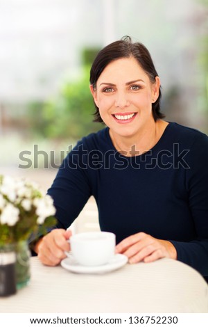 beautiful middle aged woman relaxing at home with cup of coffee