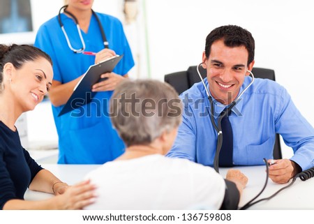 medical doctor checking senior patient\'s blood pressure