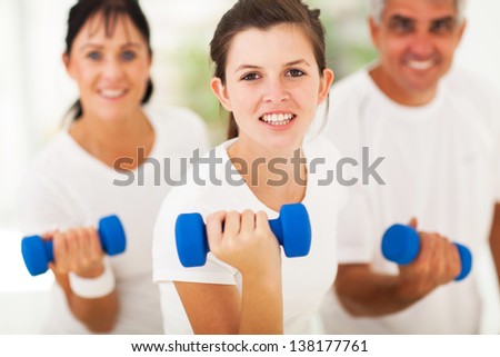 pretty teen girl working out using dumbbell with parents