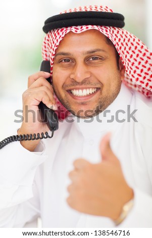 arabic businessman talking on landline phone and giving thumb up