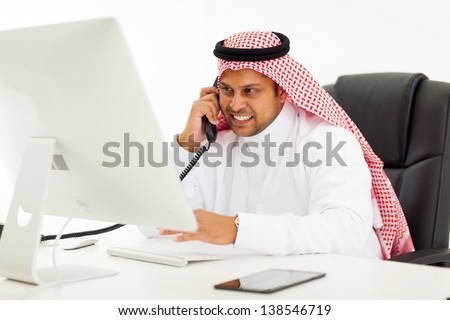 handsome arabian businessman talking on landline phone in office