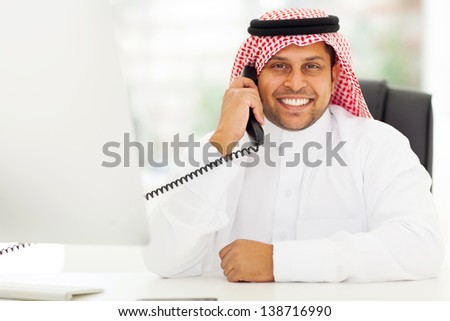 happy male arab corporate worker talking on the landline phone
