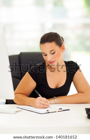 pretty business woman writing report in modern office
