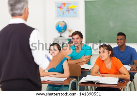 rear view of high school teacher teaching students in classroom