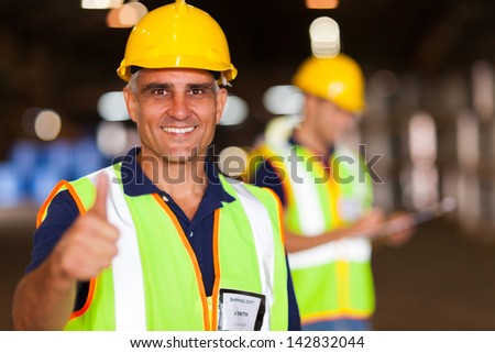 senior shipping company worker giving thumb up inside warehouse
