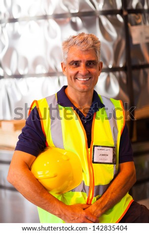 portrait of senior shipping company worker holding his helmet in warehouse