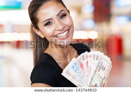happy young woman holding fan of cash on casino background