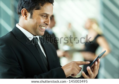 handsome indian business executive working on tablet computer in office