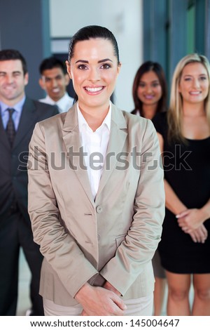 beautiful female business leader with team standing on background