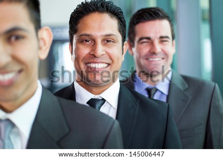 three smiling businessmen standing in a row