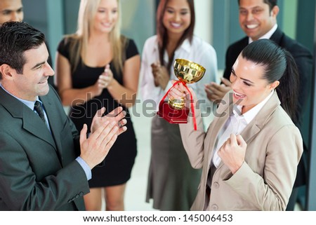 beautiful cheerful female corporate worker receiving a trophy from company CEO