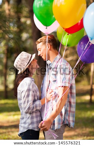 lovely teen boyfriend and girlfriend with helium balloons in forest