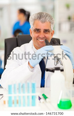 smiling senior scientist working on microscope in lab