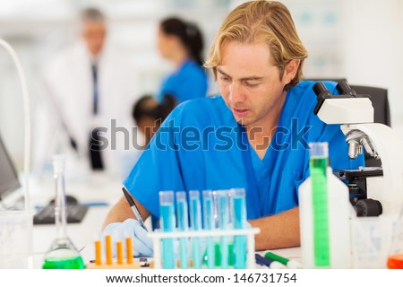 male researcher writing medical report in lab