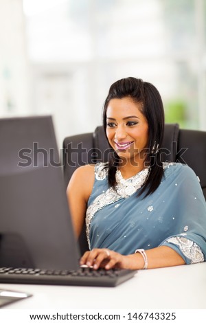 happy indian woman in traditional clothing using computer at work