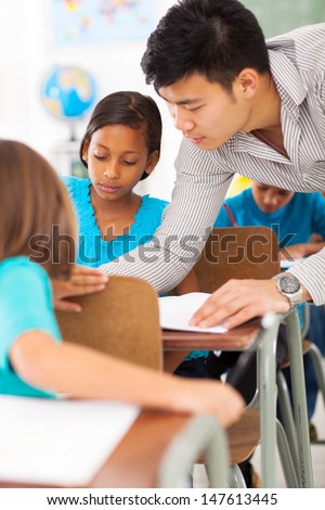 caring primary educator helping a student in classroom