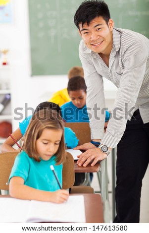 smiling elementary school male teacher in classroom with students